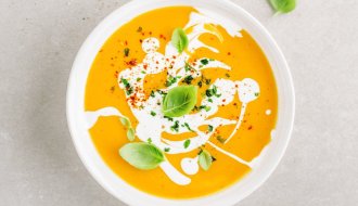 Bowl of creamy crock pot carrot soup topped with basil