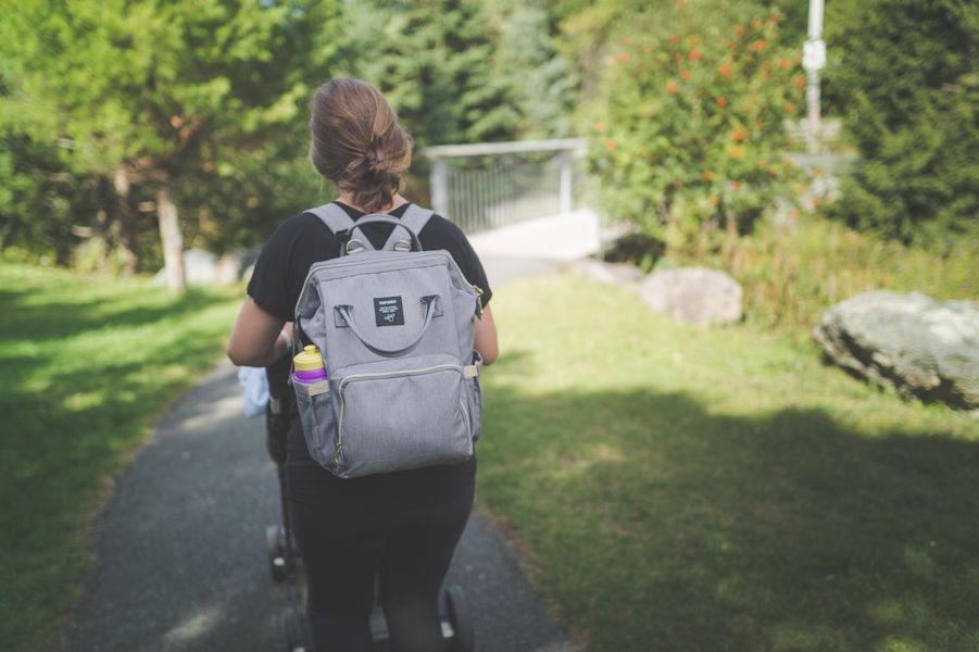 A mom walking outdoors with a stroller during postpartum recovery