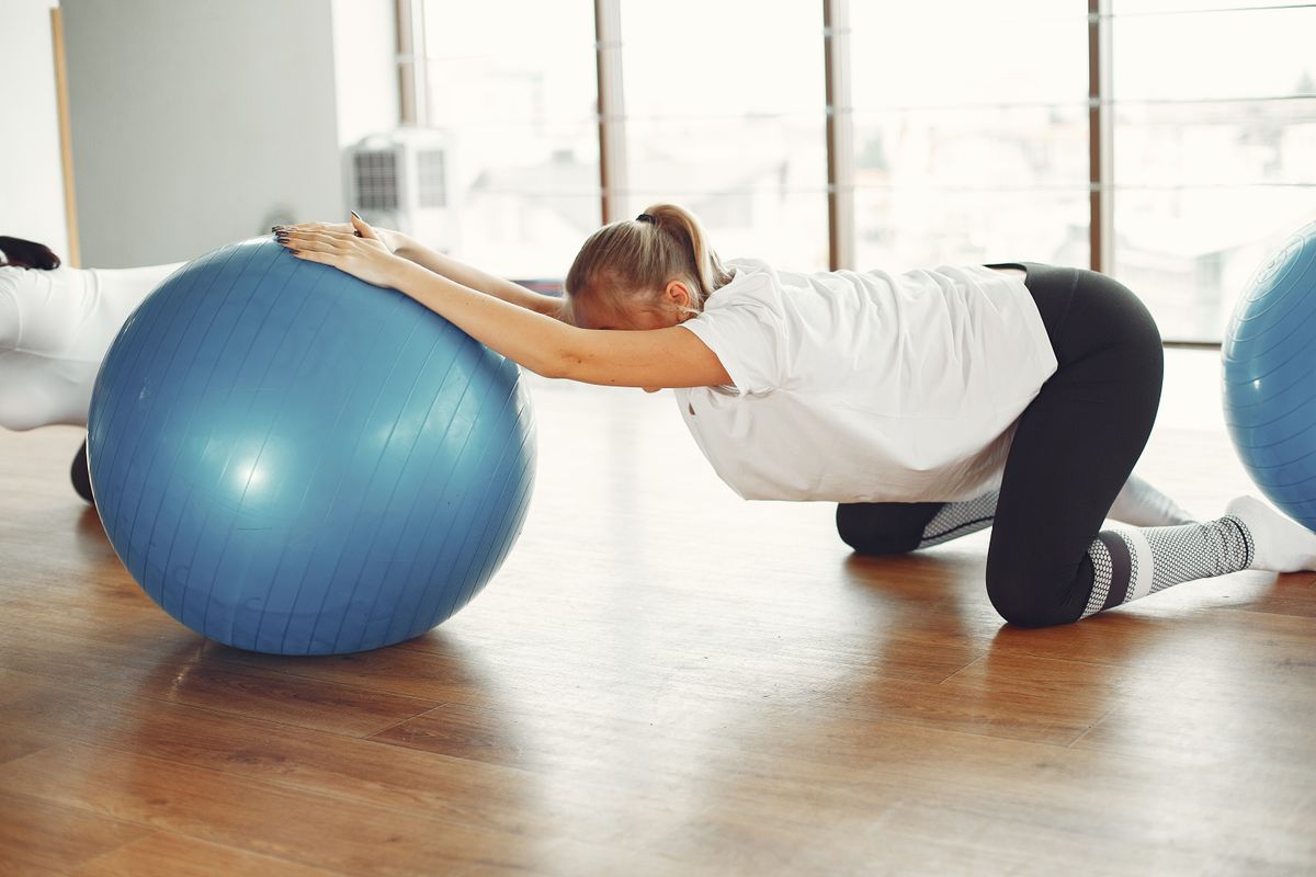 Pregnant woman in her third trimester doing a supported strength exercise with an exercise ball